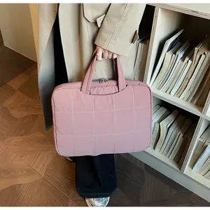 Close-up of pink quilted laptop handbag with square stitching and sturdy handles
