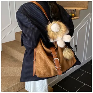 Detail of a brown woven leather hobo bag with a cute plush lion charm on a shoulder strap