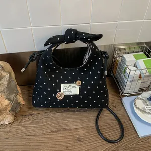 Detail van een handtas met stippen, een grote strik als handvat en een hondenfpatch