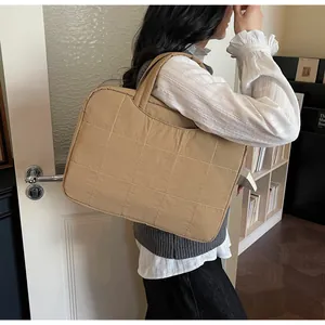 Detailed close-up of khaki quilted laptop tote bag with padded texture and dual handles