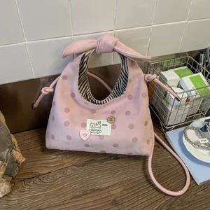 Detail van roze polkadottas met strikhandvat en zwart-wit gestreepte binnenvoering