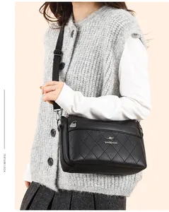 Detalle del bolso bandolera de cuero acolchado negro con logo de canguro y correa