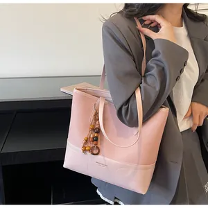 Detail der rosa Kontrast-Tote-Bag mit Wildledertextur und dekorativem Holzperlenanhänger