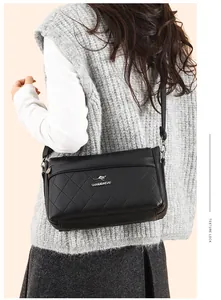 Bolso bandolera de cuero acolchado negro con logo de canguro plateado usado por modelo