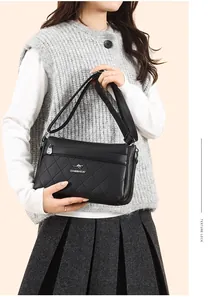 Detalle de bolso bandolera de cuero acolchado negro con logo de canguro dorado y correa