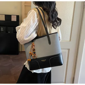 Detail der grauen Canvas-Tasche mit schwarzem Lederbesatz und Holzperlen-Quasten