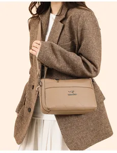 Detalle del bolso de hombro en cuero caqui con costuras acolchadas y logo metálico