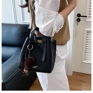 Borsa a secchiello in pelle martellata nera con ciondolo a pompon indossata da modella