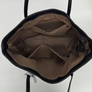 Interior detail of large tote bag showing brown lining with zip pocket and open slot