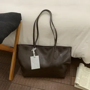 Detail of coffee brown leather tote bag showing grainy texture and puppy charm