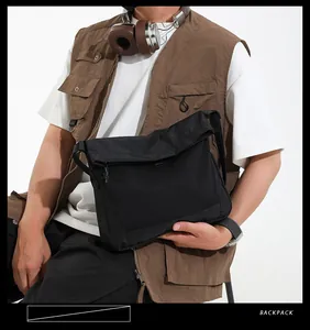 Close-up of black canvas messenger bag with mesh pocket shown in a techwear style