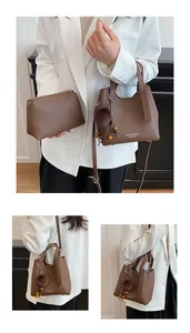 Borsa a secchiello in pelle marrone con pochette interna, pompon e tracolla con perline