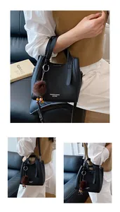 Dettaglio borsa a secchiello in pelle nera martellata con charm pompon e logo