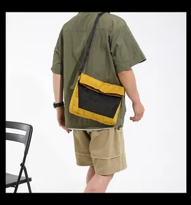 Detail of yellow nylon messenger bag with black mesh pocket on male model in utility shirt