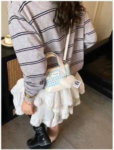 Détail du mini sac seau à carreaux bleus et blancs avec breloque cœur en peluche