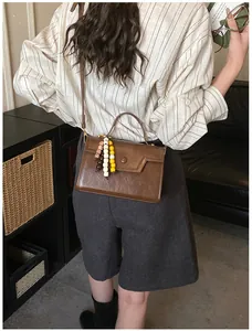 Retro brown crossbody bag with colorful bead charms and top handle on a casual outfit