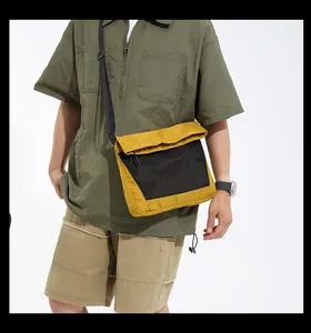 Close-up of yellow and black nylon messenger bag worn on shoulder by a model