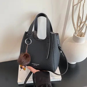 Borsa a secchiello minimalista in pelle nera con manico e ciondolo a sfera di pelo