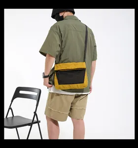 Male model wearing a mustard yellow crossbody canvas bag with black mesh pocket detail