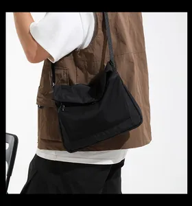 Detail view of black technical messenger bag with breathable mesh pocket and nylon strap