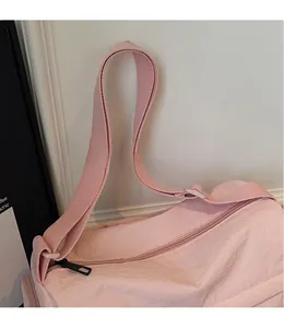 Detail of pink nylon crossbody bag showing smooth adjustable strap and metallic zipper