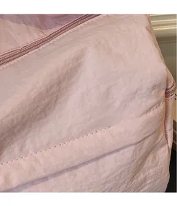 Close-up of pink lightweight quilted fabric texture and premium resin zipper detail