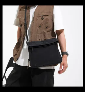 Detail of black techwear crossbody bag with mesh zip pocket and adjustable strap