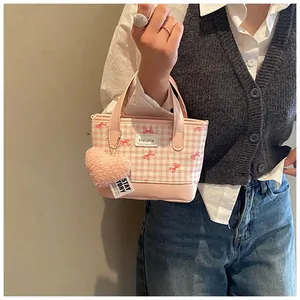 Gros plan du sac seau à carreaux roses avec imprimé nœud et charme de cœur peluche