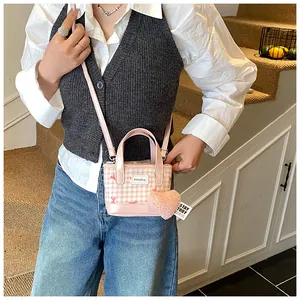 Détail du mini sac seau à carreaux rose avec breloque cœur et logo sur la bandoulière