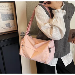 Side view of a pink nylon crossbody bag worn by a model with a casual outfit