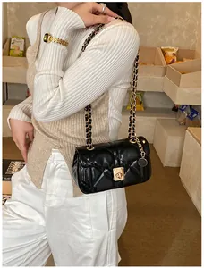 Detail of black quilted leather shoulder bag with gold chain and metal twist lock