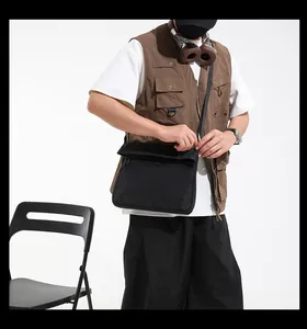 Detail of black tactical messenger bag with waterproof fabric and flap closure on model