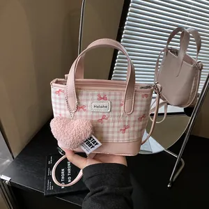 Sac seau rose à carreaux avec breloque cœur et bandoulière réglable porté à la main