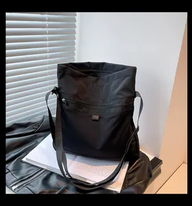 Detail of black nylon crossbody bag with front zipper pocket on leather jacket