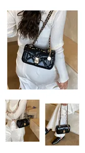 Detail of black quilted leather shoulder bag with gold chain strap and metal lock