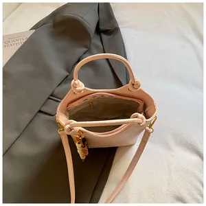 Bolso tipo cubo rosa minimalista con asas circulares y una correa de hombro ajustable