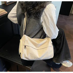 Detail of a beige nylon crossbody bag featuring multiple functional zipper pockets and strap