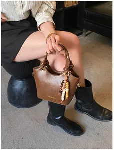 Primer plano detallado del bolso de cuero vintage marrón con colgante de cuentas y asa trenzada