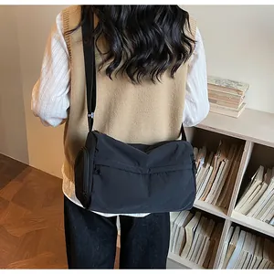 Rear view of model wearing large black nylon crossbody bag in a cozy library setting