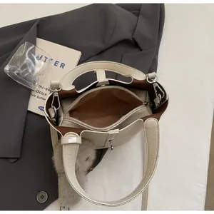 Close-up of beige lychee leather bucket bag showing brown lining and zip compartment