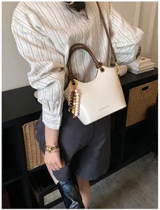 Bolso chic de cuero crema con asa trenzada marrón y detalle de cuentas de madera