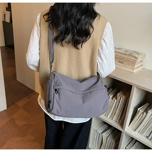 Detail of grey-purple nylon crossbody bag showing the adjustable strap and side zipper pocket