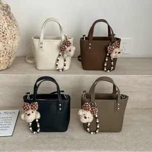 Retro trapezoid bucket handbags with teddy bear charms in beige, brown, and black colors