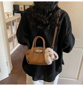 Detail of brown lychee leather tote featuring a silver metal lock and plush bunny charm