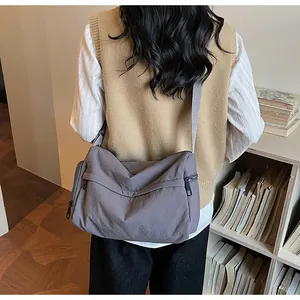 Detail of gray-purple crossbody messenger bag with durable fabric and multiple zippers