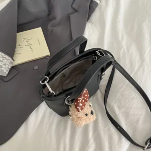 Retro black textured leather bucket bag with plush bear charm and silver hardware accents