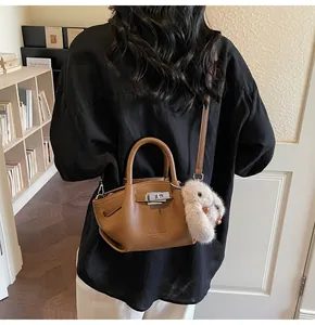 Detailed shot of brown textured leather bag with silver buckle and plush rabbit charm