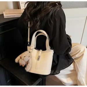 Detail of white lychee pattern bucket bag featuring metal lock and plush charm