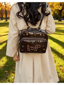 Détail d'un sac à dos marron foncé avec broderie de teckel dans un parc naturel