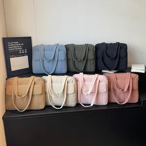 Minimalistische gesteppte Laptop-Tasche in sieben Farben auf einem Etagenständer